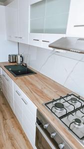 a white kitchen with a stove and a sink at Cosy apart 3 Fagaras in Făgăraş