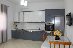 a kitchen with blue cabinets and a table with flowers at Diar Sea House in Orikum