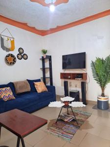 a living room with a blue couch and a fireplace at Homey Stay in Kampala