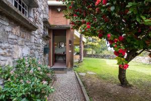 a door to a building with a tree with red roses at Parco Hermitage - Vila Camelia in Porto Valtravaglia