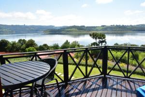 a table and chair on a balcony with a view of a lake at Cabanas Lago - Piratuba-SC in Piratuba