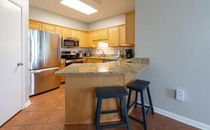 a kitchen with a refrigerator and two bar stools at Phoenix VI 6004 in Orange Beach