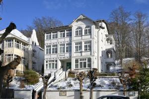 a large white house with snow on the ground at DÜNENHAUS Sellin in Ostseebad Sellin