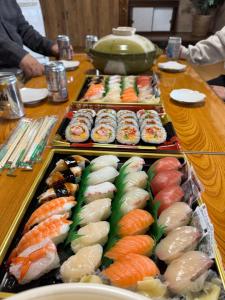 a table topped with trays of sushi and vegetables at ぺろんち in Shinkamigoto