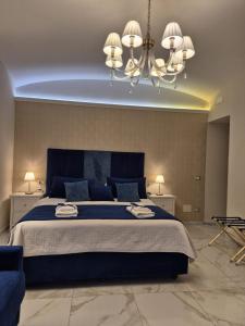 a bedroom with a large blue bed with a chandelier at Napoli Sogno Infinito in Naples