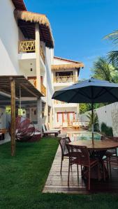 a patio with a table and chairs with an umbrella at Vila Marina Icaraizinho in Icaraí