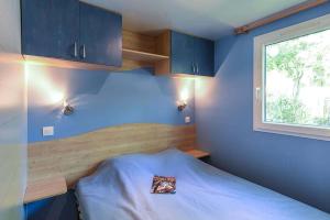 a bedroom with a bed with blue walls and a window at Camping Le Pavillon bleu in L'Aiguillon-la-Presqu'île