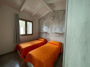 two beds in a room with orange sheets at Villetta Maluva - Budoni in Budoni