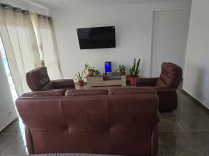 a living room with a brown couch and two chairs at Chez Fortes in Porto Novo