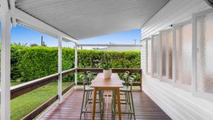a porch with a wooden table and stools on it at White Cockatoo Beachfront Cottage in Newell Beach