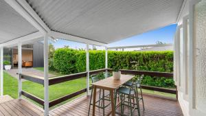 a patio with a table and chairs on a deck at White Cockatoo Beachfront Cottage in Newell Beach