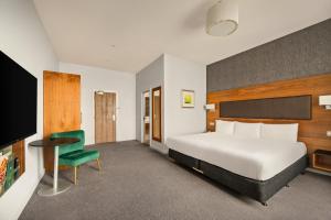 a hotel room with a bed and a green chair at Holiday Inn Newcastle-Jesmond by IHG in Newcastle upon Tyne +93 photos