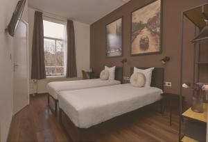 a hotel room with two beds and a window at Quentin Canal House Hotel in Amsterdam