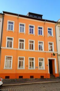 un bâtiment orange avec des fenêtres blanches sur une rue dans l'établissement Haus am Schloßberg, à Plauen