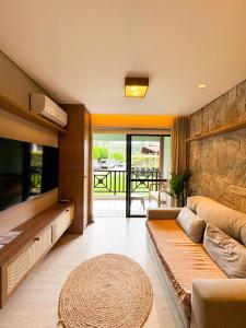 a living room with a couch and a flat screen tv at Chalé Mar e Sol, Marina e Resort Angra in Angra dos Reis