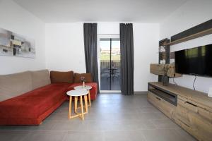 a living room with a red couch and a tv at Apolo Apartments - Pool & Garden Retreat in Pula