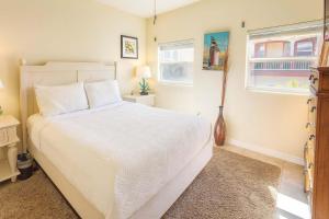 a bedroom with a white bed and two windows at Pompano Beachview Home home in South Padre Island