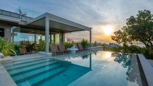 a house with a swimming pool with the sunset in the background at Hotel Petit Bois - Adults from 14 in Balatonfüred