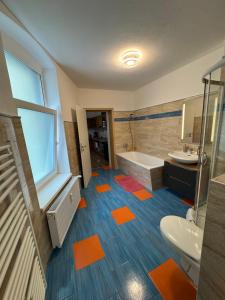 a bathroom with orange and blue floors and a tub and sink at Ferienwohnung Florion 2 in Bernburg +5 photos