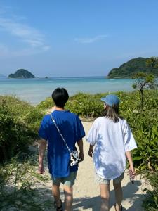 a man and a woman walking down a beach at ぺろんち in Shinkamigoto