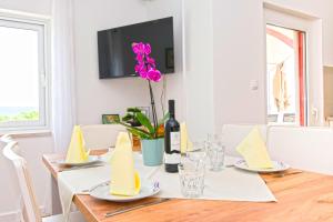 a dining room table with a bottle of wine and a flower at Apartments Miljenko in Dobropoljana