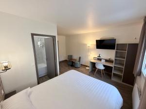 a hotel room with a bed and a desk at Hotel ARBOR - Les Hunaudieres - Le Mans Sud - Mulsanne in Mulsanne
