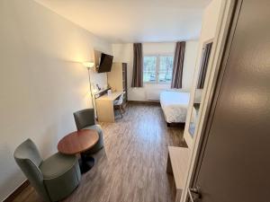 a hotel room with a bed and a table and chairs at Hotel ARBOR - Les Hunaudieres - Le Mans Sud - Mulsanne in Mulsanne +37 photos