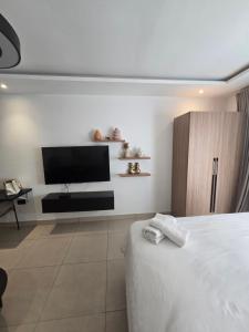 a bedroom with a bed and a flat screen tv at Belrose Place in Accra