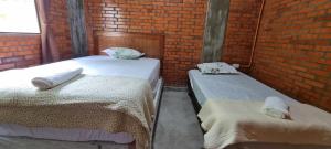 two beds in a room with a brick wall at Alojamiento Mariana y Ocho Oñondive in Villa Concepción
