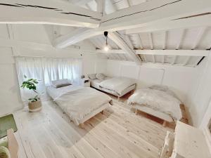 two beds in a room with white walls and wood floors at Guest House DETARAMESO in Yamakami
