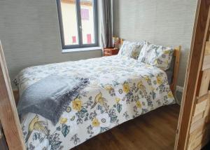 a bedroom with a bed with a floral bedspread at Lit et Croissants in Bertignat