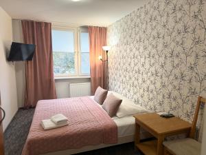 a bedroom with a bed with a pink blanket and a window at Sosnowe Zacisze in Białystok
