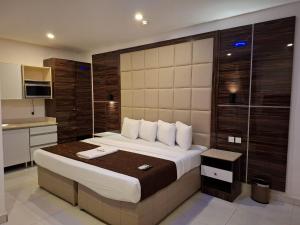 a bedroom with a large bed and a kitchen at Presken Apartment Ikoyi in Lagos
