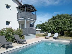 a house with a swimming pool with chairs and a balcony at Apolo Apartments - Pool & Garden Retreat in Pula