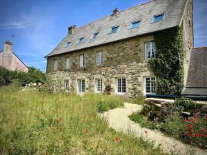 an old stone building with windows and a field of flowers at Charming house in an old rectory PMR in Tréguier