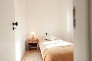 a bedroom with a bed and a table with a lamp at Republica House in Trafaria