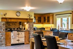 a kitchen with a table and a clock on the wall at Finest Retreats - Oak Leaf Cottage in Beaworthy