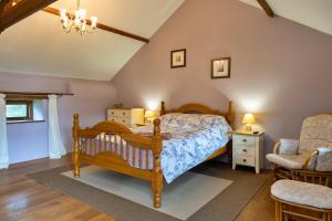 a bedroom with a wooden bed and a chair at Finest Retreats - Oak Leaf Cottage in Beaworthy