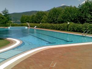 a large swimming pool with blue water at Parco Hermitage - Vila Camelia in Porto Valtravaglia