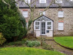 a brick house with a white door and a yard at Vosporth Villa in Newquay