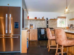 a kitchen with a stainless steel refrigerator and wooden cabinets at Vosporth Villa in Newquay