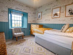 a bedroom with a bed and a chair and a window at Vosporth Villa in Newquay