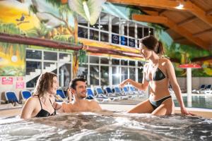 a man and two women sitting in a hot tub at Hotel Fürdőház in Nyíregyháza