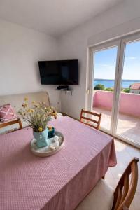 a table with a pink table cloth and flowers on it at Apartmani Čop Rab in Banjol