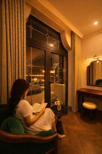 a woman sitting in a chair reading a book at OCEAN HOTEL Ninh Binh - Near Trang An & Hoa Lư Old Town in Kỳ Vĩ +90 photos