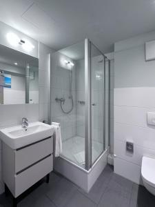 a white bathroom with a shower and a sink at Townhouse Düsseldorf in Düsseldorf