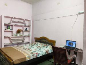 a bedroom with a bed and a desk with a laptop at Garden Villa, Hyderabad in Hyderabad