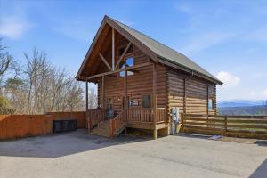 a log cabin with a porch and a fence at Smoky Mountain Bliss by Beyond Expectations in Sevierville