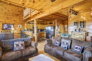 a living room with couches and a kitchen in a cabin at Smoky Mountain Bliss by Beyond Expectations in Sevierville