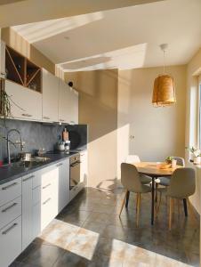 a kitchen with white cabinets and a table and chairs at GLEDKA Apartament in Veliko Tŭrnovo +6 photos